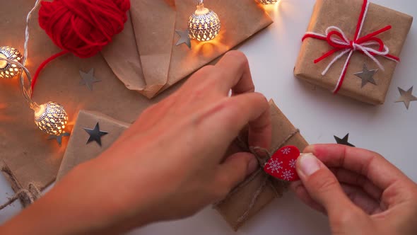 Woman Is Wrapping Present Box with Craft Paper and Red Paper Clip. Christmas and New Year Background alt