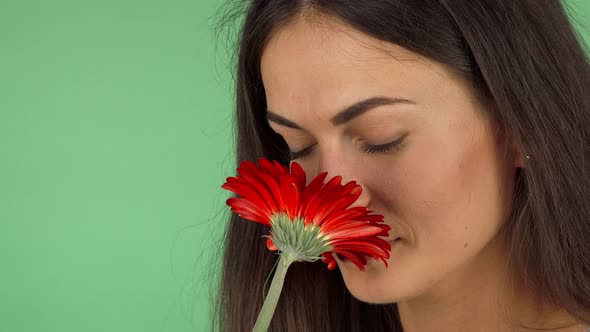 Attractive Cheerful Woman Smelling a Flower and Smiling alt