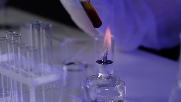 Close-up of hand pharmaceutical holding tube with chemical material burner fire alt
