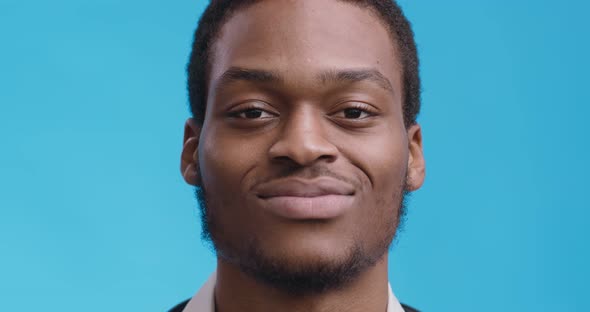 Close Up Portrait of Cheerful African American Guy Smiling To Camera, Blue Studio Background alt