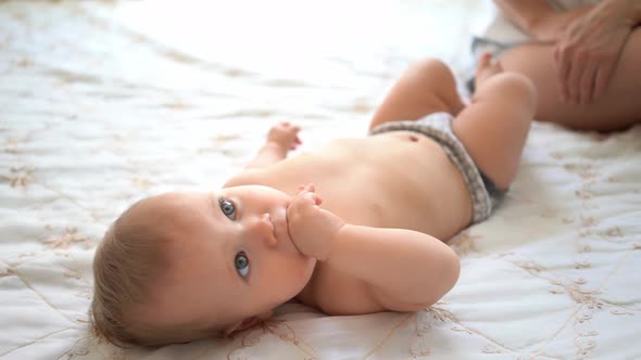 Baby Wearing Pants Lying on Bed. alt