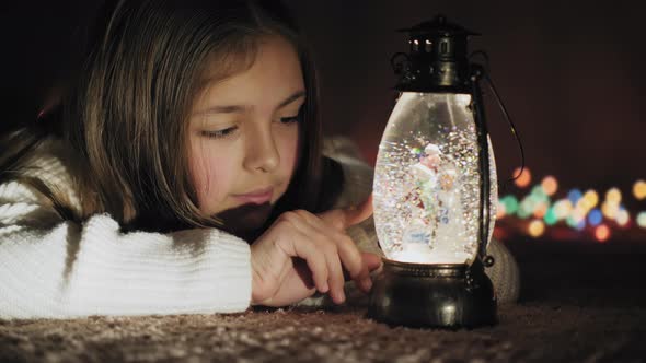 Christmas Snow Globe and Cute Girl Watching Snowflakes and Lights alt