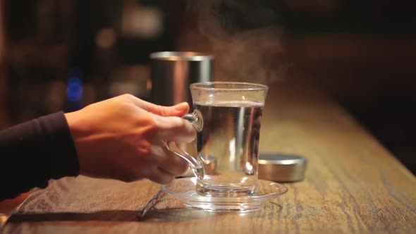 Woman placing a glass of hot water on a counter