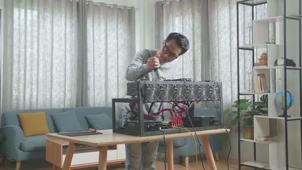 Asian Man Wearing Glasses Cleans The Mining Rig For Mining Cryptocurrency alt