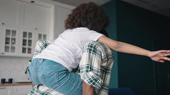Happy African American Father Riding His Little Daughter on Back Girl Pretending to Be Plane alt