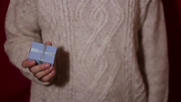 Beautiful Girl Twists a Gift in Her Hands in a Small Blue Box alt