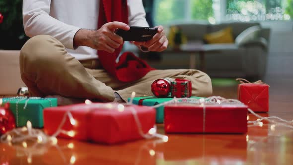 Asian man using mobile taking a photo gift box and upload to the internet in the living room at home