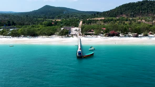 Aerial of long tail boat docked at wooden pier on 4k Beach, Kong Rong, Cambodia alt