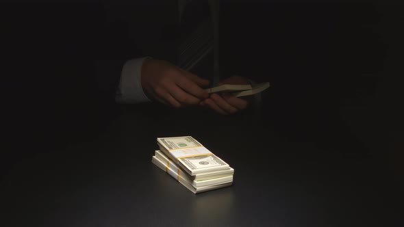 Businessman counts and puts down a heap money on a table