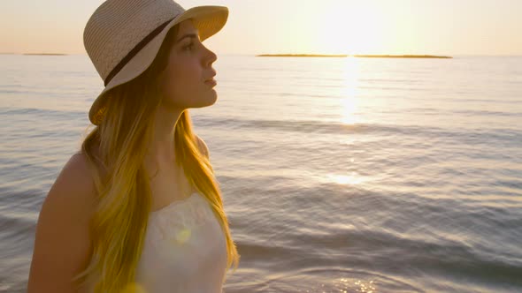 Steadycam shot of a Young attractive woman walking on the beach during sunset alt