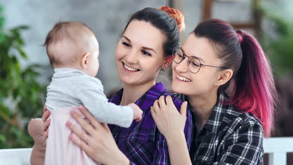 Happy Female Parents Holding Little Son Playing and Admiring Cute Baby Medium Closeup alt
