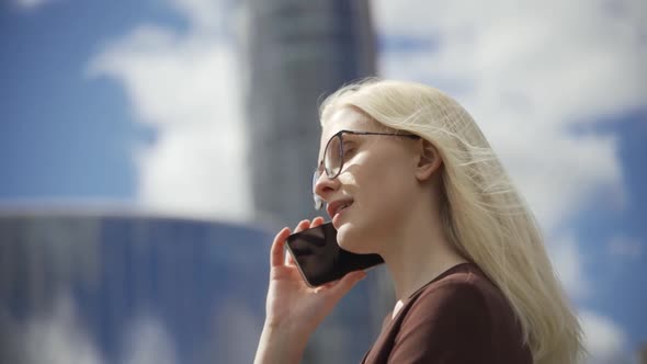 Caucasian Confident Young Business Woman is Talking on Phone Outside Near Modern Office Building