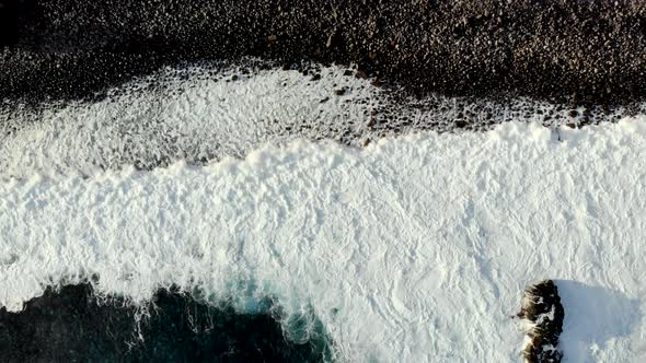 Aerial Top Down View of Waves Foaming on Rocky Coastline