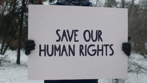 Single picket of a person in gloves holding the banner Save Our Human Rights alt