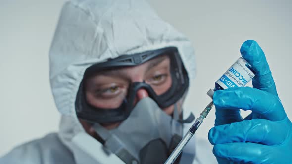 Doctor in Protective Clothes Fills Syringe with Coronavirus vaccine.Search for Treatment and alt