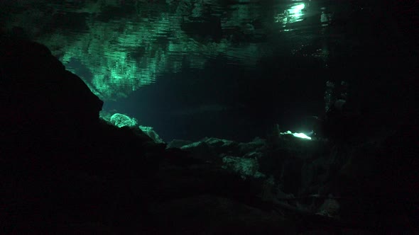Scuba Divers in Cave system Cenote Tajma Ha in Yucatan Mexico and reflection on water surfacce alt