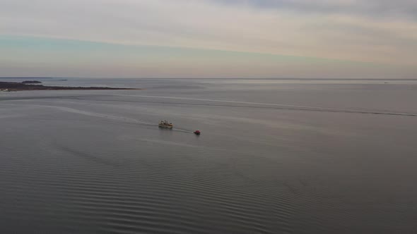 an aerial view of Long Island Sound in Orient Point, NY. A ship is being towed by a tugboat on a clo alt