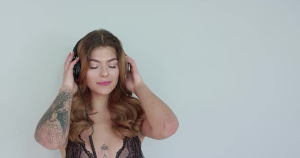 Woman Puts Headphones Over Her Ears Reacts to the Music and Subtely Sways Along alt