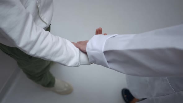 High Angle View Unrecognizable Boy and Pediatrician Taking Hands Walking Away in Slow Motion alt
