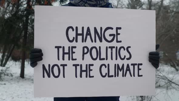 An Activist in a strike is carrying a sign Change The Politics Not The Climate alt