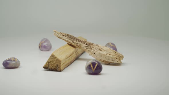 Two Pieces Of Palo Santo Wood Surrounded By Purple Gem Stones Moving In A Circular Motion - Close Up alt