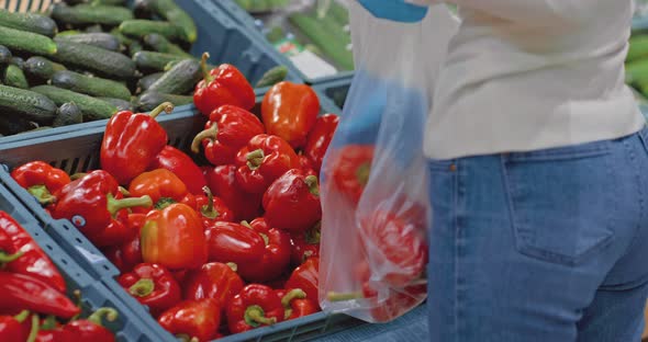 Closeup a Woman's Hand in Medical Gloves Takes Vegetables From a Supermarket Shelf alt