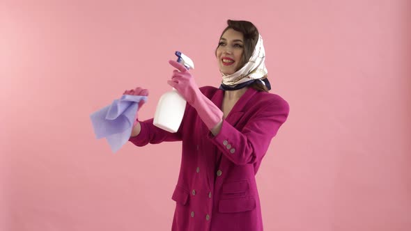 A Happy Young Woman in Gloves Washes the Windows with a Spray