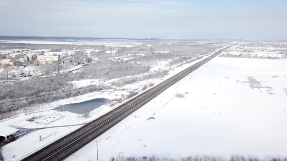 Winter Time Aerial Top Down View of a Snowy Road Surrounded Pine Tree Forest alt