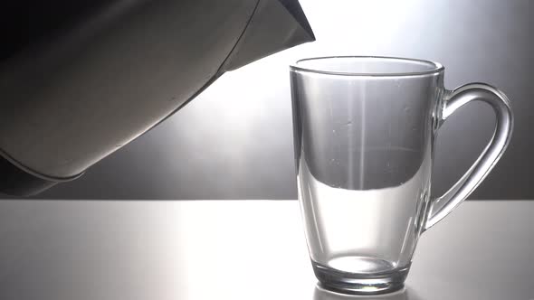 Pour Hot Water From the Electric Kettle Into a Glass Mug alt