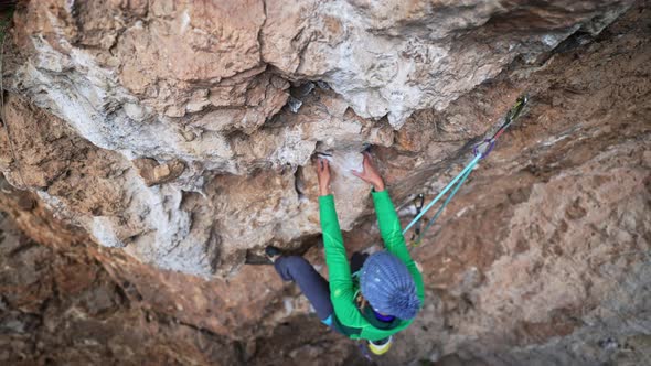 Slow Motion From Above of Woman Rock Climber Climbs on Overhanging Cliff By Hard Route alt