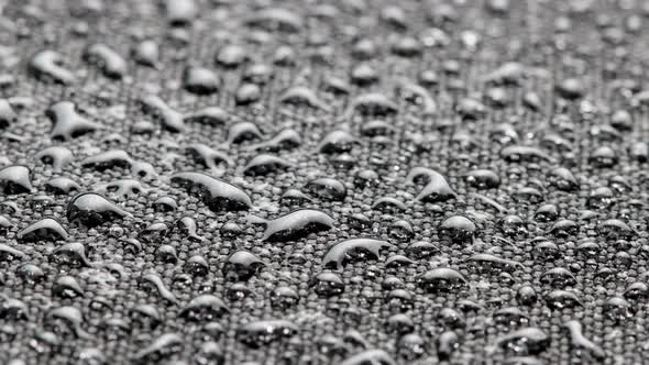 Spinning Closeup Background of Black Hydrophobic Fabric Covered with Water Drops