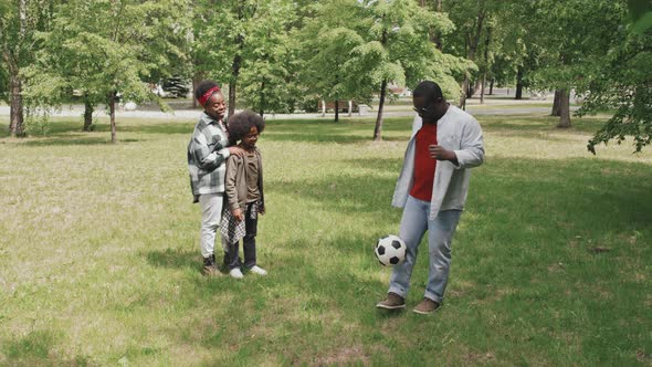 African American Man Kicking Football Outdoors alt