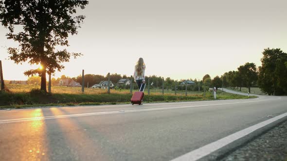Cheerful Woman with Suitcase Walking on Road. alt