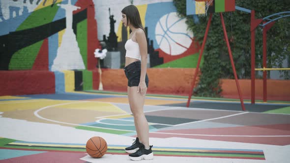 Wide Shot of Slim Young Woman Warming Up on Outdoor Basketball Court alt