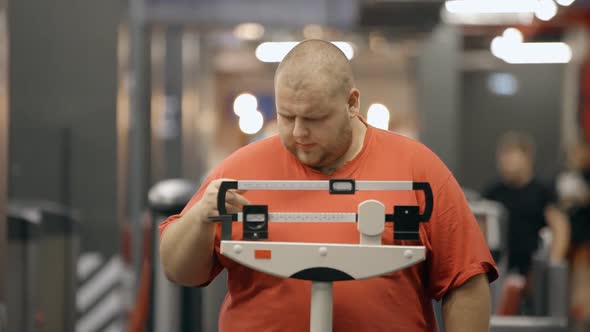 Attractive and Overweight Man Standing on a Mechanical Scale