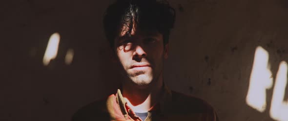 Man standing by the wall, looking towards camera, close up alt