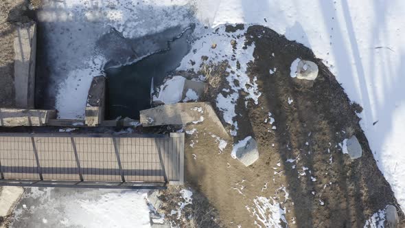 Mother Holding Baby Walking Across River Bridge Snowy Day Aerial Drone Top Down View alt