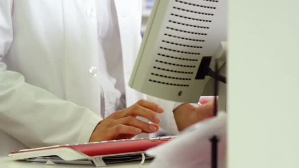 Pharmacist making prescription record on computer alt