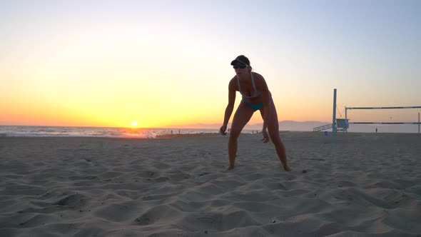 Women players play beach volleyball and a player digs the ball. alt