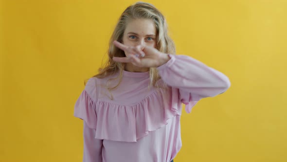 Portrait of Attractive Young Blonde Dancing Moving Hands on Yellow Background alt