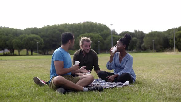 Cheerful Colleagues Drinking Coffee on Lawn During Coffee Break alt