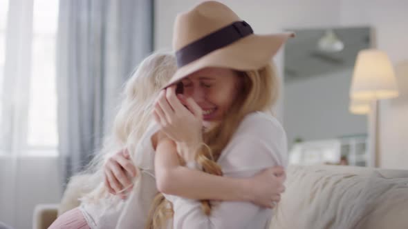 Excited Little Girl Hugging Mother on Couch and Laughing alt