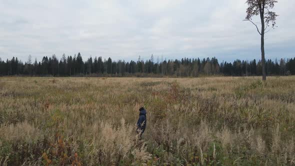 Woman in a Blue Jacket Walks Through an Autumn Field alt