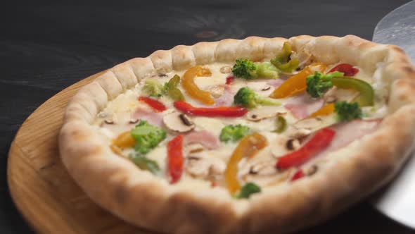 Pizza with a Steel Shovel is Placed on a Brown Wooden Tray