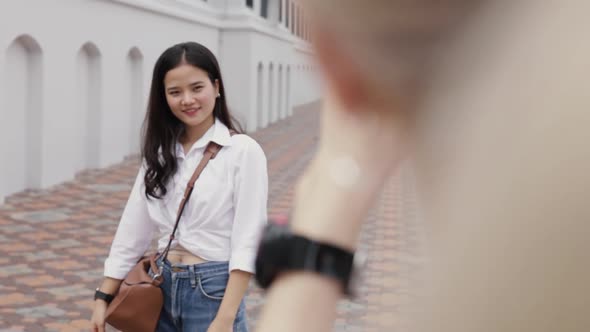 Asian lesbian couples enjoying traveling using a smartphone taking a photo.