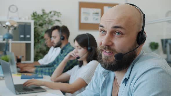 Attractive Guy Wearing Headset Talking to Client Working in Technical Customer Support in Office alt