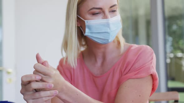 Mother and daughter wearing face masks sanitizing their hands at home alt