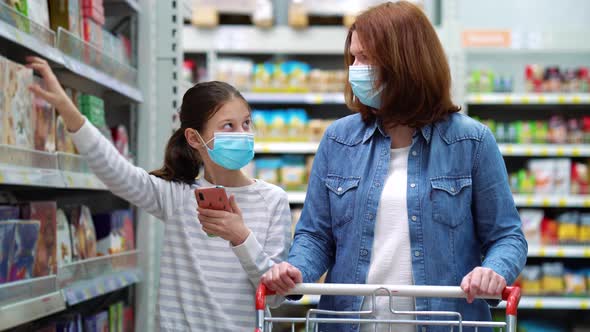 Mother and daughter buying sweets in supermarket during pandemic