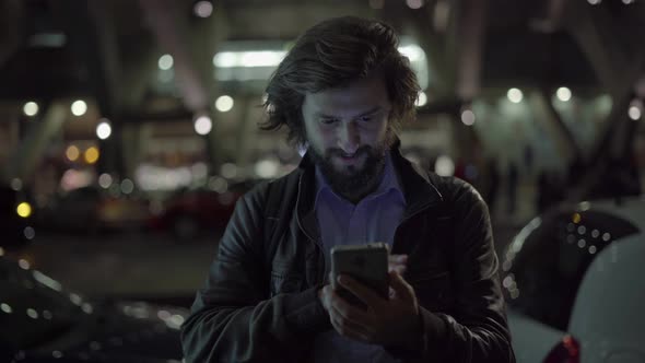 Smiling Caucasian Man Using Gadget at Night in Urban City alt