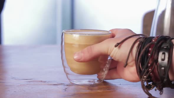 Female hand take a cup of latte coffee in a cafe. Visitor's hand taking a cup in restaurant.